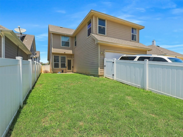 rear view of house featuring a garage and a lawn