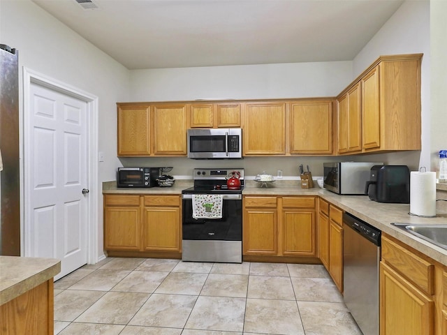 kitchen featuring appliances with stainless steel finishes, sink, and light tile patterned floors