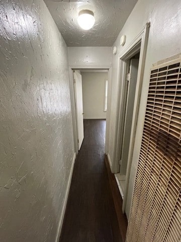 corridor with dark hardwood / wood-style flooring and a textured ceiling