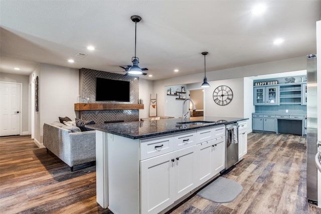 kitchen with sink, tasteful backsplash, hanging light fixtures, a center island with sink, and white cabinets