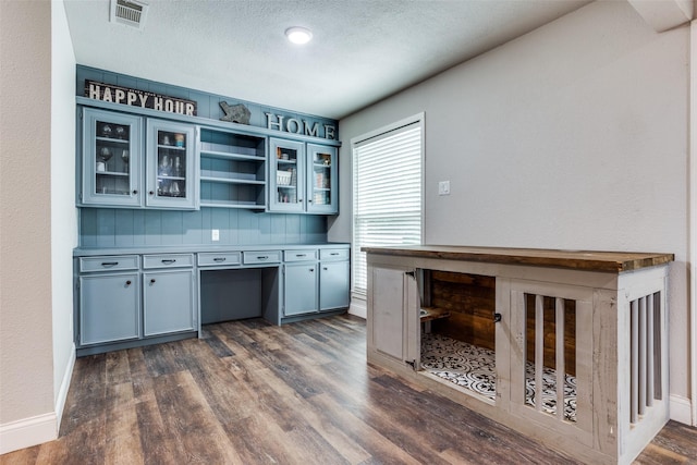 kitchen featuring dark wood-type flooring, gray cabinets, a textured ceiling, and built in desk