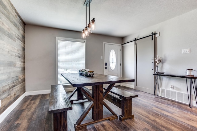 dining area featuring a barn door, dark hardwood / wood-style flooring, and a wealth of natural light