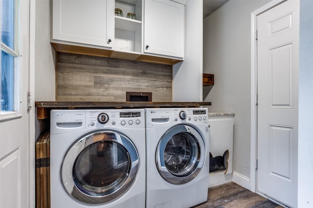 clothes washing area with dark hardwood / wood-style flooring, washing machine and dryer, and cabinets