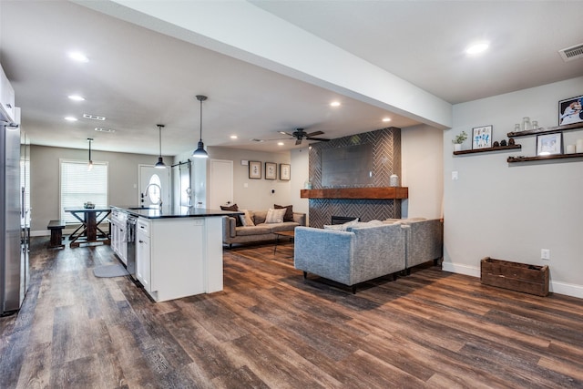 living room with a tile fireplace, dark wood-type flooring, sink, and ceiling fan