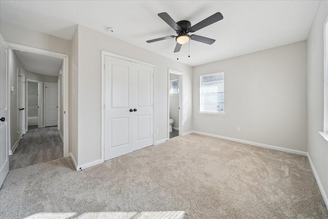 unfurnished bedroom featuring carpet floors, ensuite bath, baseboards, and a closet