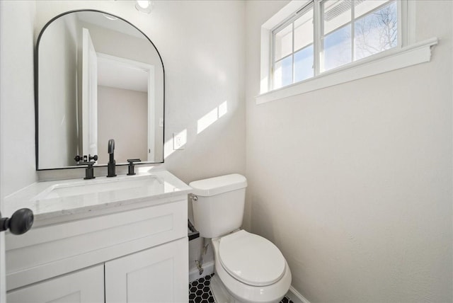 bathroom with vanity, toilet, and baseboards