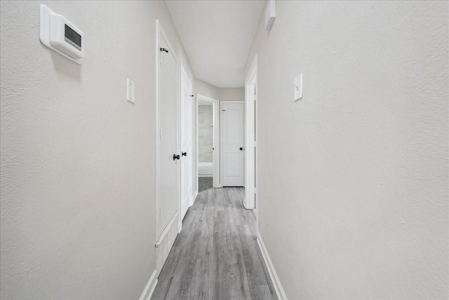 hallway featuring baseboards and wood finished floors