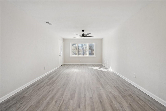 unfurnished room featuring a ceiling fan, wood finished floors, visible vents, and baseboards