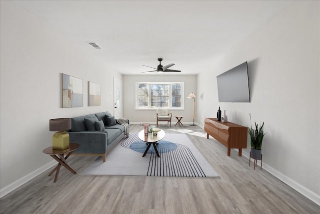 living room with a ceiling fan, baseboards, visible vents, and wood finished floors