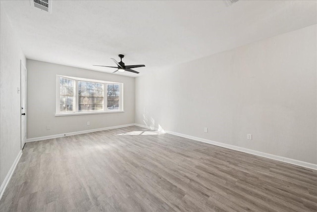 spare room with visible vents, ceiling fan, baseboards, and wood finished floors