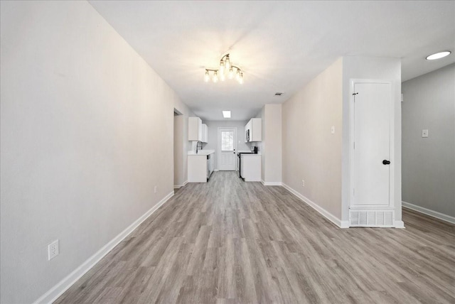 unfurnished living room featuring visible vents, a chandelier, light wood-style flooring, and baseboards