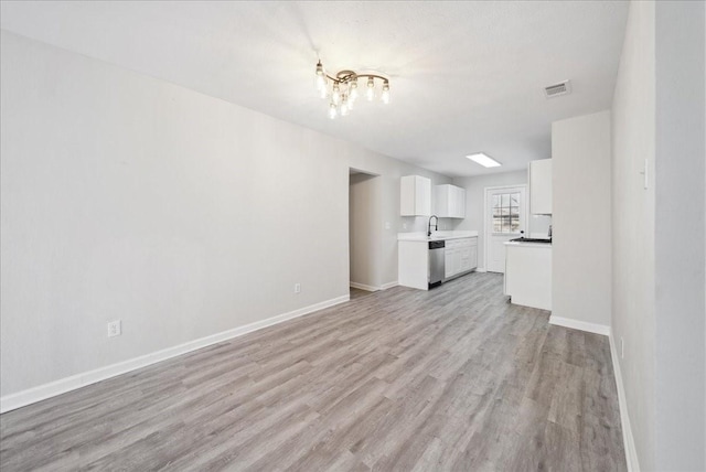 unfurnished living room featuring a sink, visible vents, baseboards, light wood-type flooring, and an inviting chandelier