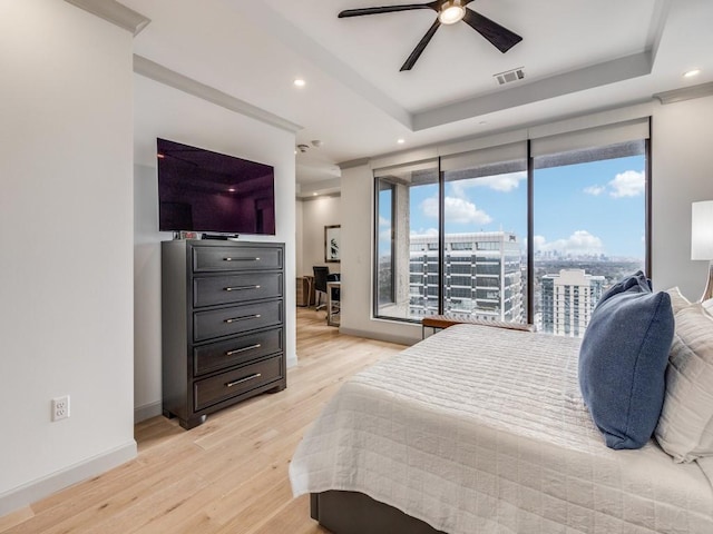 bedroom featuring a raised ceiling, light wood-type flooring, access to exterior, and ceiling fan