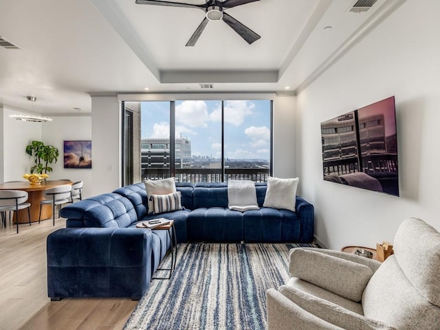 living room featuring a raised ceiling, floor to ceiling windows, hardwood / wood-style floors, and ceiling fan