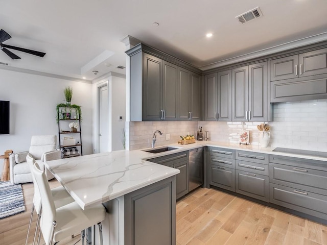 kitchen with sink, light wood-type flooring, stainless steel dishwasher, gray cabinets, and kitchen peninsula