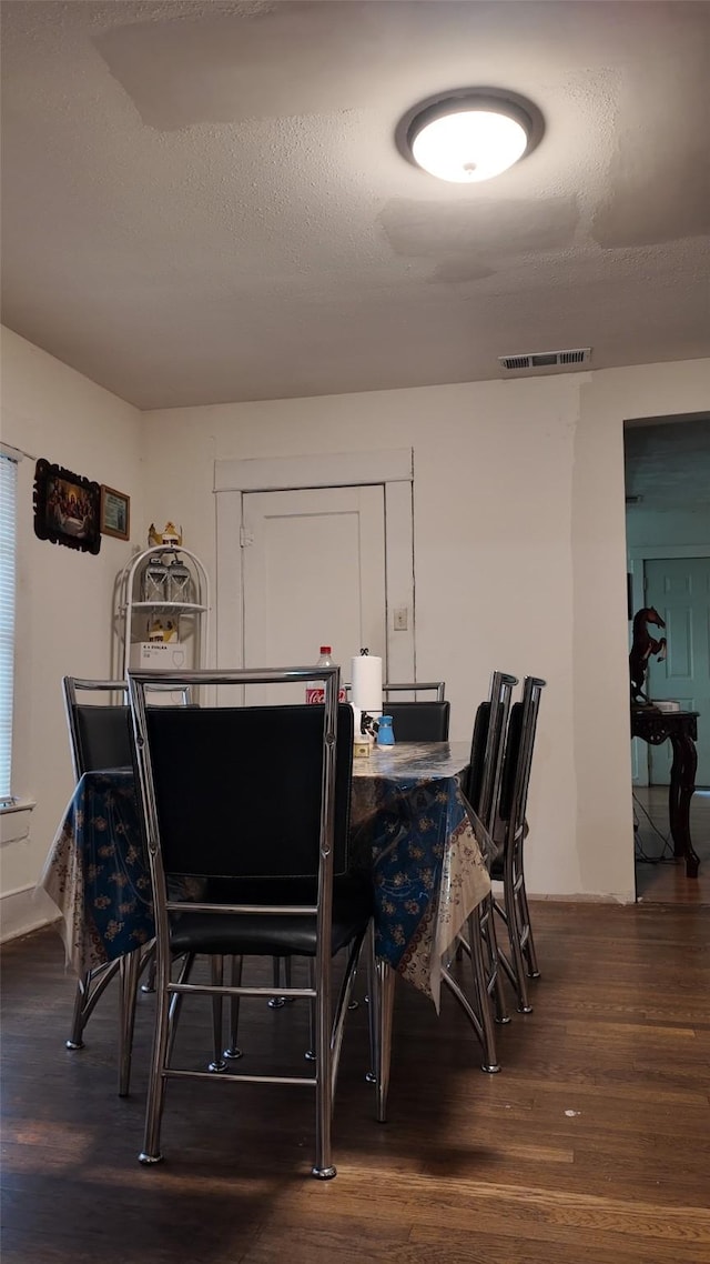 dining space featuring a textured ceiling and dark hardwood / wood-style flooring