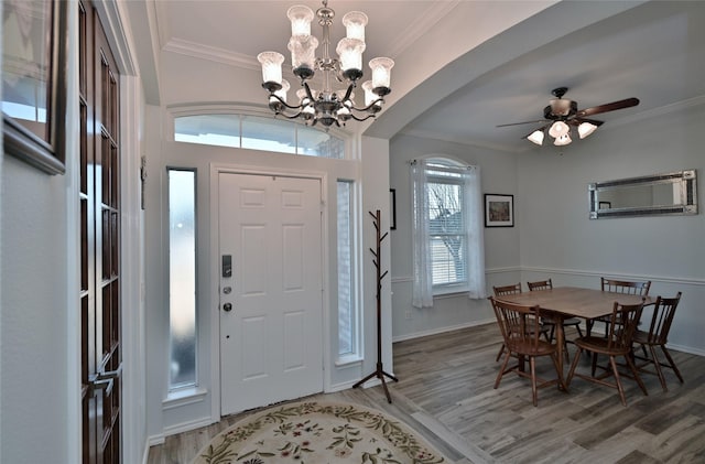 entryway featuring hardwood / wood-style flooring, ceiling fan with notable chandelier, and ornamental molding