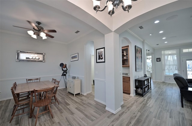 dining space featuring crown molding, ceiling fan with notable chandelier, and light wood-type flooring