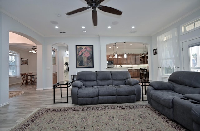 living room with ornamental molding, ceiling fan, and light hardwood / wood-style flooring