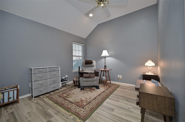 living area with ceiling fan, vaulted ceiling, and light hardwood / wood-style flooring