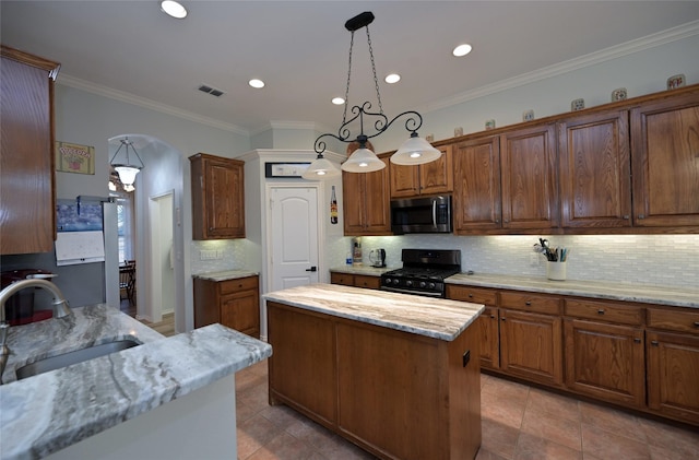 kitchen with sink, gas stove, a center island, pendant lighting, and decorative backsplash