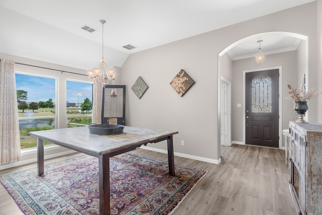 interior space with vaulted ceiling, a chandelier, ornamental molding, a water view, and light hardwood / wood-style flooring