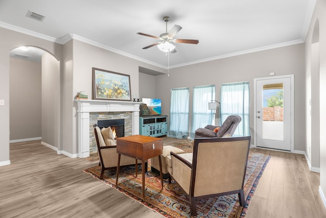 living room featuring ornamental molding, light wood-type flooring, and a fireplace