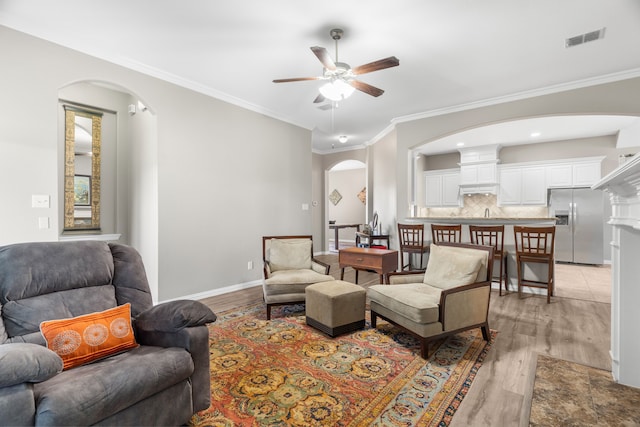 living room featuring ceiling fan, ornamental molding, and light hardwood / wood-style flooring