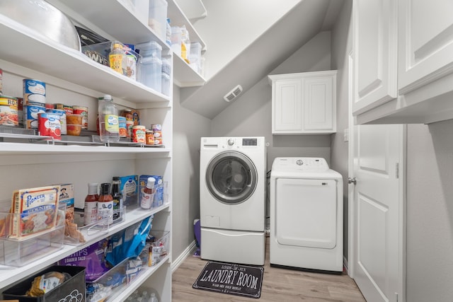 washroom featuring cabinets, washer and clothes dryer, and light hardwood / wood-style flooring