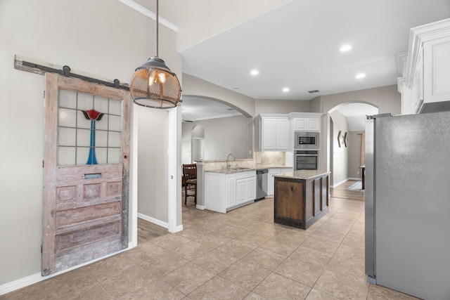 kitchen with sink, white cabinets, a center island, light stone counters, and stainless steel appliances