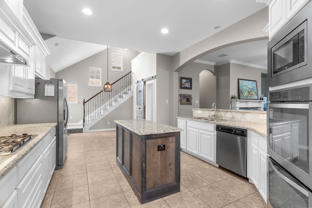 kitchen featuring sink, stainless steel appliances, a center island, light stone countertops, and white cabinets