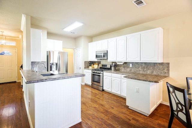 kitchen with sink, tasteful backsplash, kitchen peninsula, stainless steel appliances, and white cabinets