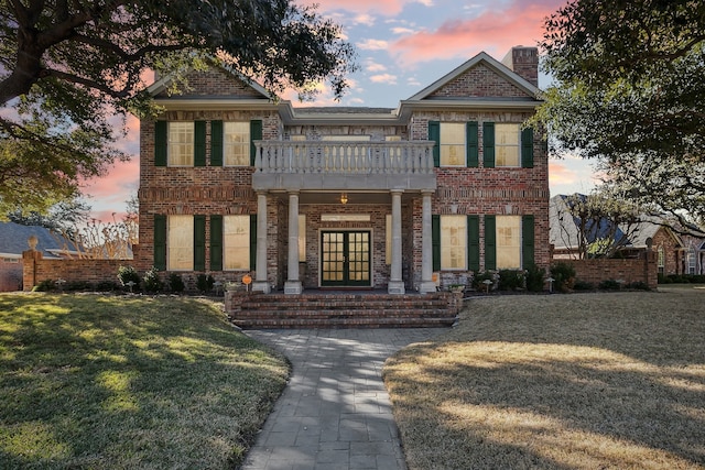 view of front of home with a balcony and a yard