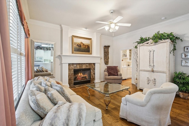 living room featuring a premium fireplace, wood-type flooring, and crown molding