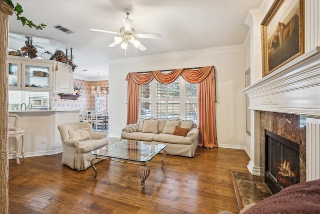 living room featuring dark wood-type flooring, a fireplace, ornamental molding, and ceiling fan