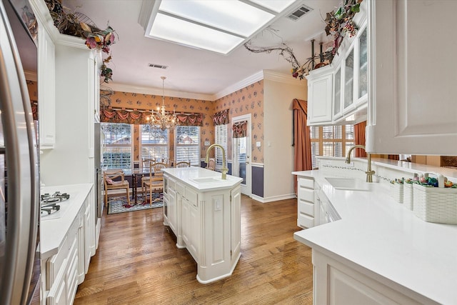 kitchen featuring a kitchen island with sink, sink, pendant lighting, and white cabinetry