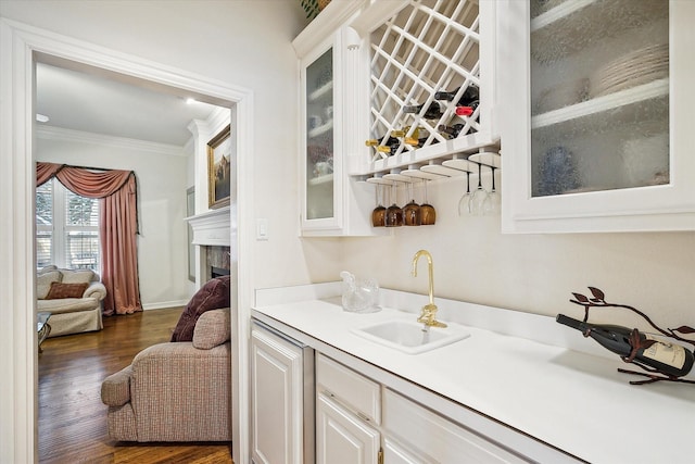 bar with white cabinetry, sink, dark wood-type flooring, and ornamental molding