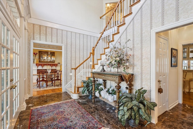 foyer entrance featuring french doors, a towering ceiling, and crown molding