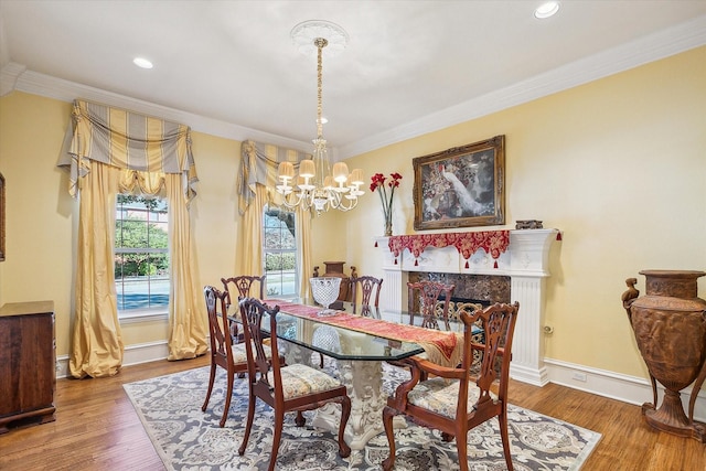 dining space with hardwood / wood-style flooring, ornamental molding, a high end fireplace, and an inviting chandelier