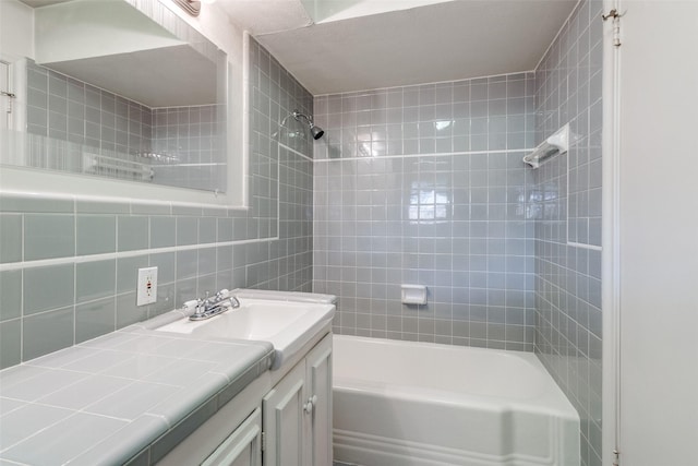 bathroom with vanity, tiled shower / bath combo, and tile walls