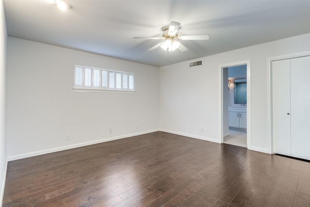 unfurnished bedroom with dark wood-type flooring, ensuite bath, and ceiling fan