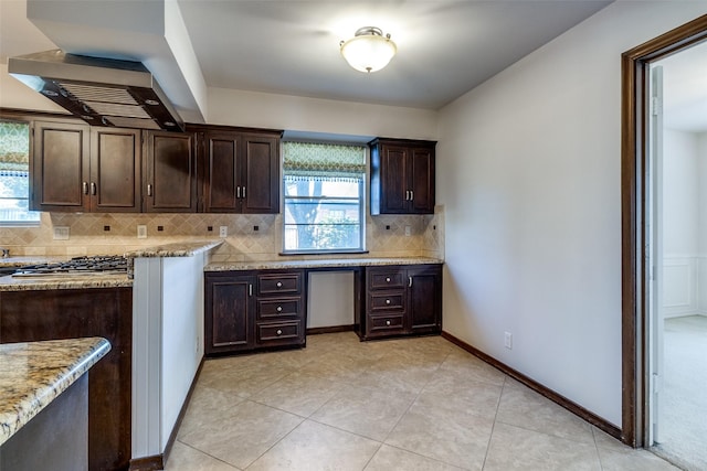 kitchen with dark brown cabinetry, light tile patterned floors, decorative backsplash, and light stone countertops