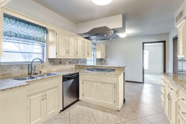 kitchen featuring sink, backsplash, range hood, stainless steel appliances, and light stone countertops