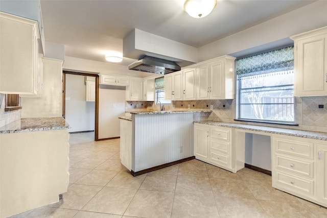 kitchen featuring sink, backsplash, light stone countertops, and light tile patterned floors