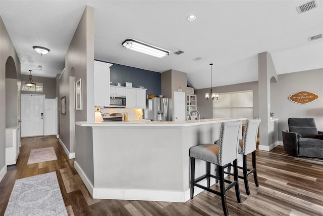 kitchen featuring dark hardwood / wood-style floors, white cabinetry, a chandelier, hanging light fixtures, and stainless steel appliances