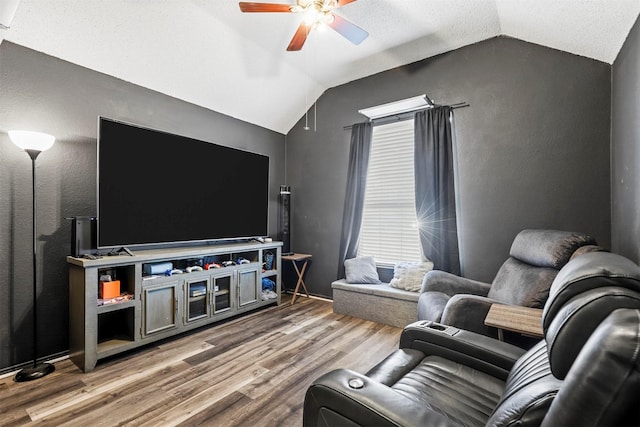 living room with vaulted ceiling, a textured ceiling, ceiling fan, and light wood-type flooring