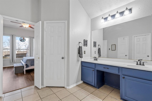 bathroom with lofted ceiling, tile patterned flooring, vanity, ceiling fan, and a textured ceiling