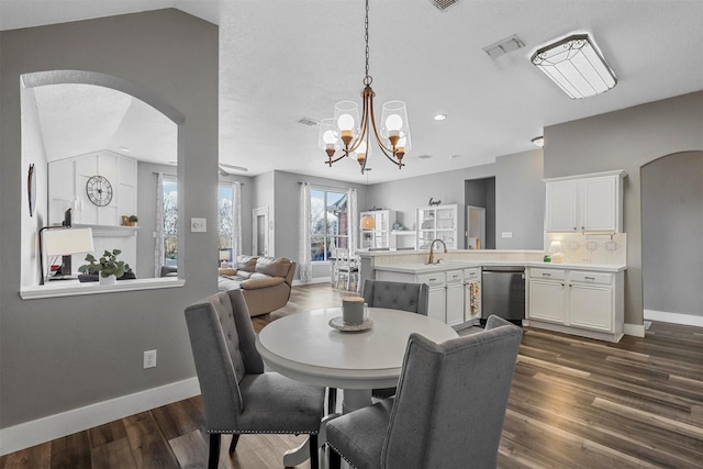 dining area featuring sink, vaulted ceiling, dark hardwood / wood-style floors, and a chandelier