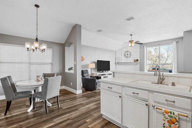 kitchen with vaulted ceiling, dark hardwood / wood-style floors, pendant lighting, sink, and white cabinets