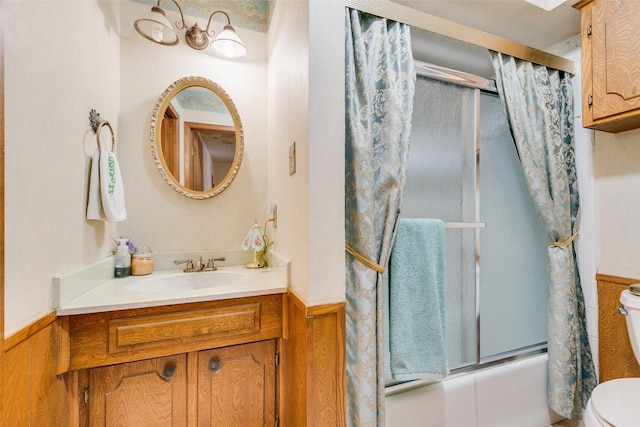 full bathroom featuring enclosed tub / shower combo, vanity, wooden walls, and toilet